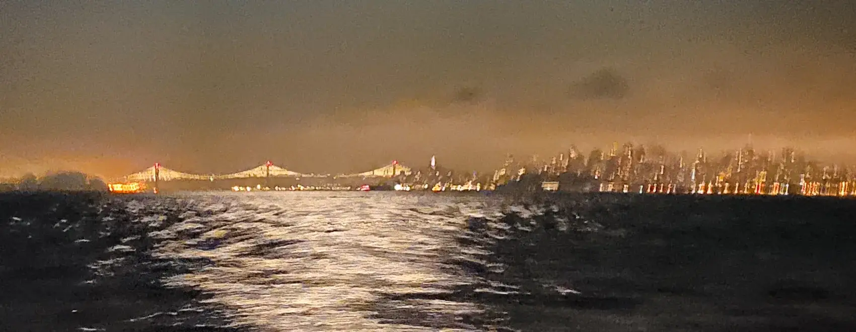Night view from an escort vessel showing the Bay Bridge and San Francisco skyline before a Round Trip Angel Island marathon swim